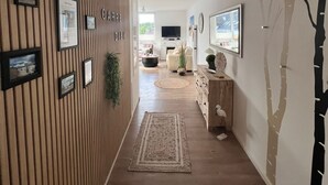 Un pasillo con pared de paneles de madera, cuadros enmarcados, un televisor y una planta.