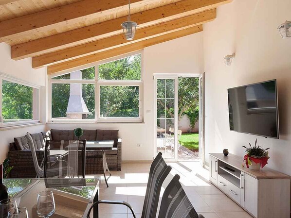 Un grand espace de vie comprenant une table à manger, des chaises, un canapé et un téléviseur.