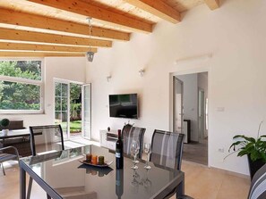 Un espace repas moderne avec une table en verre, des chaises et un téléviseur fixé au mur.