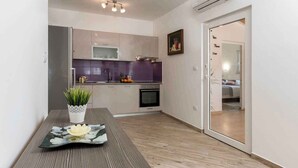 A modern kitchen with a microwave, oven, and purple backsplash. There is a dining table with a potted plant and a decorative plate. - Holiday home with Jacuzzi and air conditioning (Banjole)