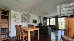 A modern living space with a dining area, a sofa, and a bookshelf.