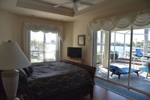 A bedroom with a bed, a TV, and a view of an outdoor pool area.