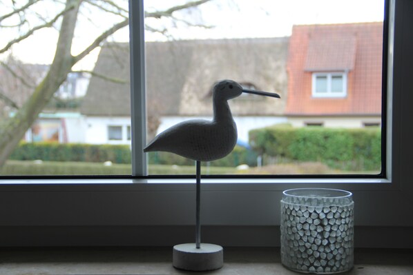 A bird figurine on a stand next to a textured vase on a windowsill. - Light-filled, comfortable apartment in a quiet central location - close to the beach (Zingst)