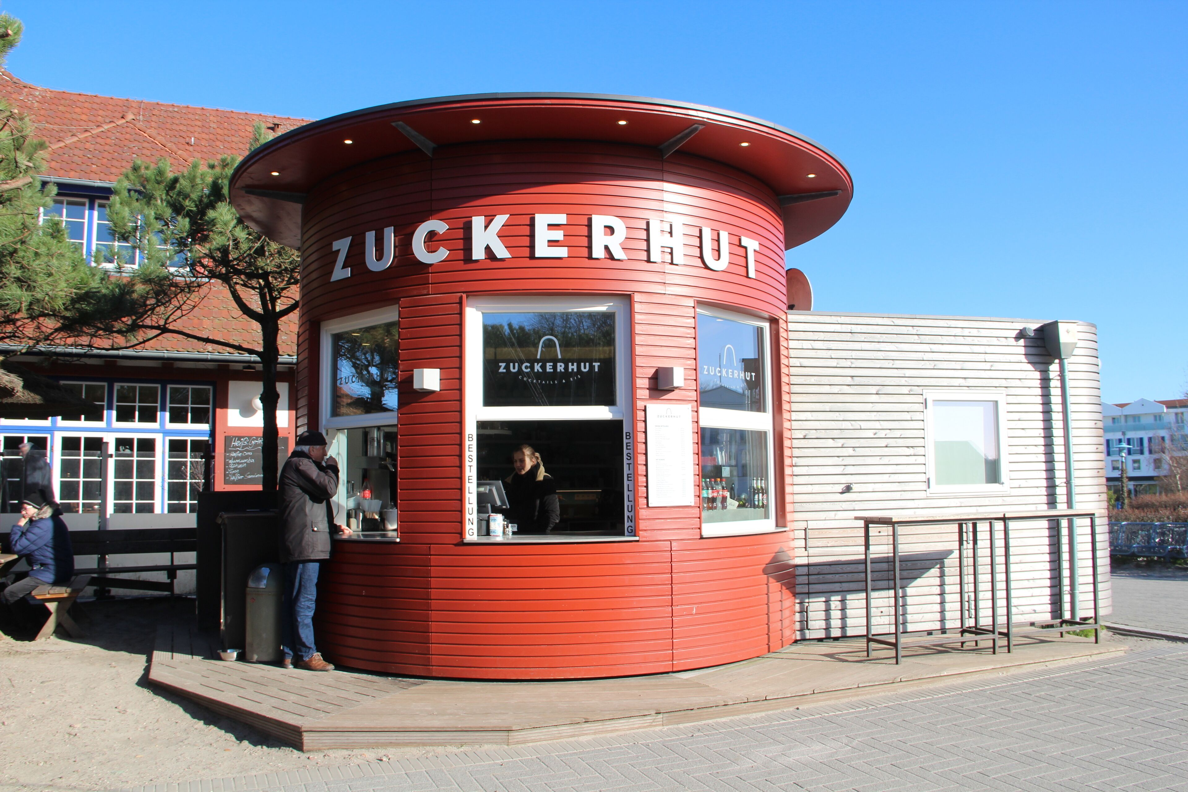 Un edificio rojo y circular con el nombre 'Zuckerhut' en la fachada.