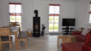 A living room with a fireplace, a television, a red sofa, and a dining area with wooden furniture.