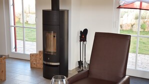 A room with a modern fireplace, a leather chair, and a glass table with a candle.