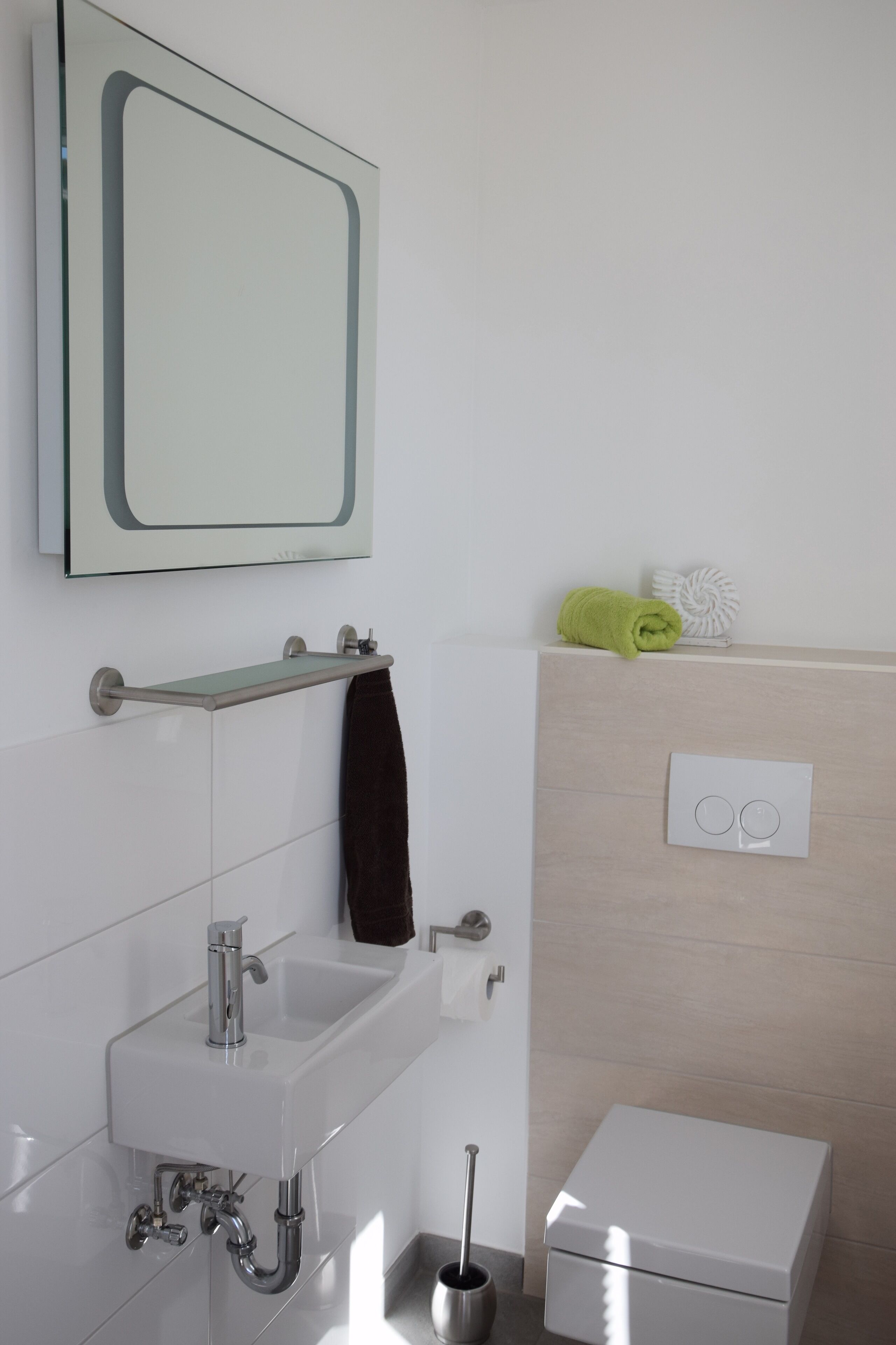 Une salle de bain moderne avec un lavabo blanc, un miroir, un porte-serviettes et un petit meuble blanc.