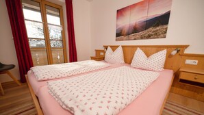 Une chambre à coucher avec un grand lit, une tête de lit en bois, une table de chevet, une chaise et une fenêtre avec des rideaux.