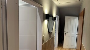 A hallway with wooden flooring, white walls, and a white door at the end.