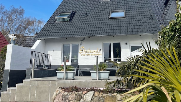A building with a sign reading "Steilsand2" and a website address.