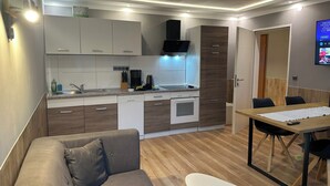 A modern kitchen with white and wooden cabinets, a built-in oven, and a dining area with a table and chairs.