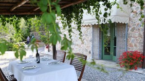 Un espace de restauration en plein air, avec une table dressée pour deux personnes, entouré de murs en pierre et de verdure.