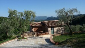 A rustic stone building with a tiled roof, surrounded by greenery and mountains in the background. - Splendio Rustico, nestled among olive and lemon trees, with a private pool. For Exclusive Use Only!! (Camaiore)