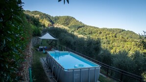A rectangular swimming pool with a white cover, surrounded by a stone deck and a metal railing. - Splendio Rustico, nestled among olive and lemon trees, with a private pool. For Exclusive Use Only!! (Camaiore)