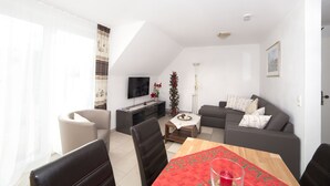 Een moderne woonkamer met een eethoek, een zithoek, een televisie en een kerstboom.