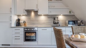Een moderne keuken met witte kasten, een inbouwoven en een magnetron.
