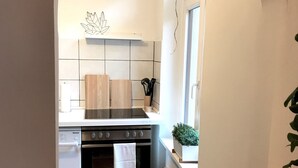 Eine kleine Küche mit Herd, Backofen und einem Fenster.