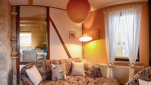 Ein gemütliches Zimmer mit einer Couch, einem Fernseher und einer Steinsäule.