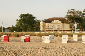 A beach with numbered beach chairs and a large building in the background. - Vacation in a quiet apartment, yet only 300 m to the beach (Kühlungsborn)