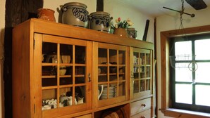 A wooden cabinet with glass doors containing various kitchenware. - Holiday in 300 years old, listed mill in an idyllic location (Hofheim in Unterfranken)