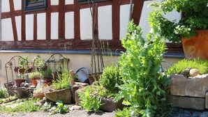A garden with various potted plants and gardening tools in front of a half-timbered building. - Holiday in 300 years old, listed mill in an idyllic location (Hofheim in Unterfranken)