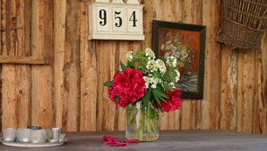A wooden wall with a number sign, a vase with flowers, and a tray with cups. - Holiday in 300 years old, listed mill in an idyllic location (Hofheim in Unterfranken)