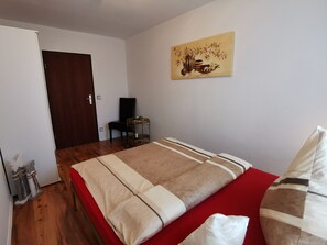A bedroom with a bed, a chair, a small table, and a painting on the wall.