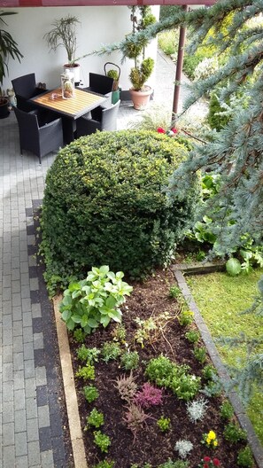 A patio area with a wooden table and chairs, surrounded by potted plants and a well-maintained garden.