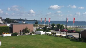 Ein Hotel an der Küste mit Parkplatz, Flaggen und Blick auf das Meer.