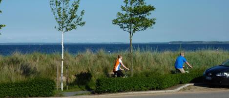 A coastal road with two cyclists and a parked car.
