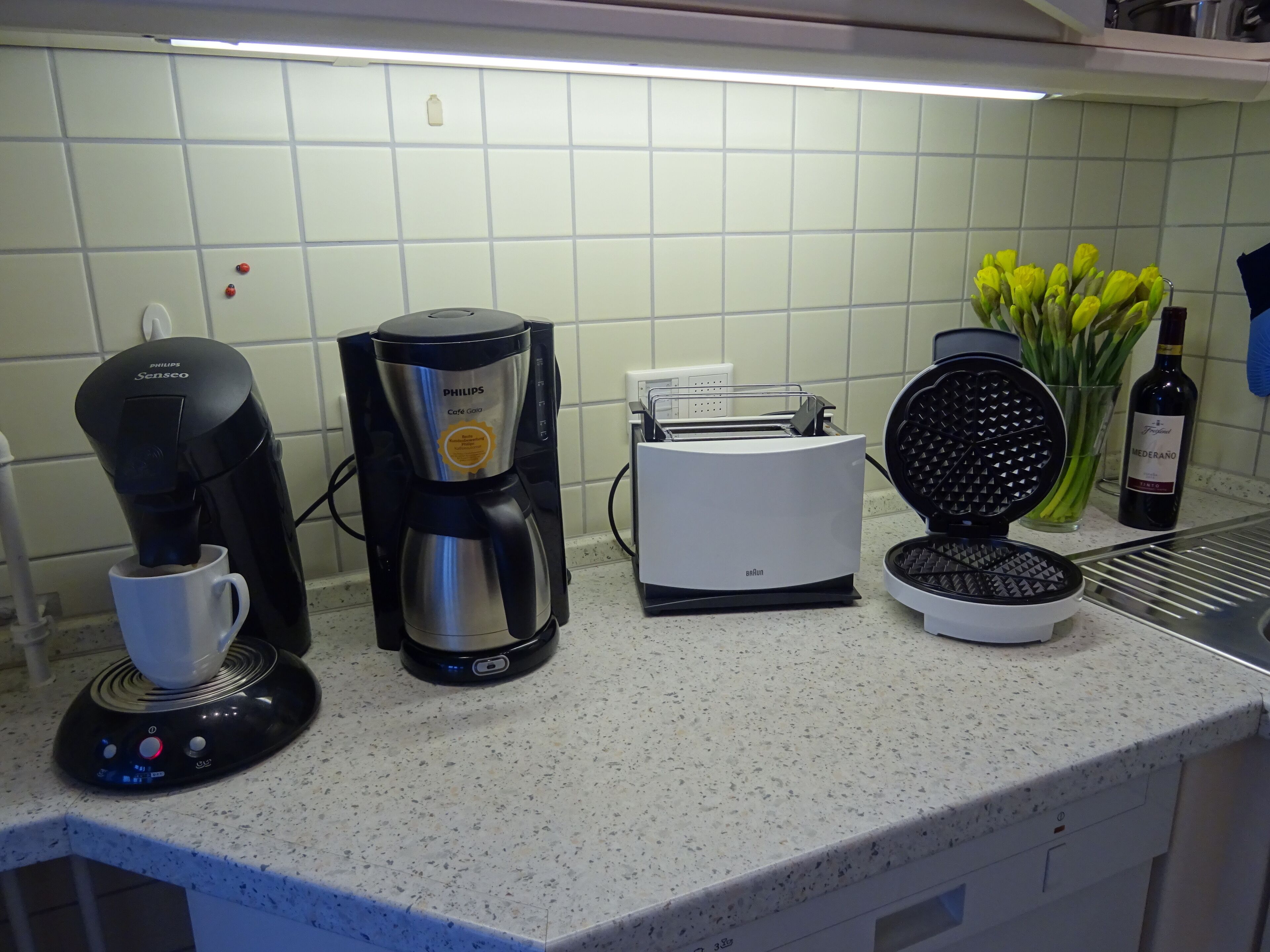Un plan de travail de cuisine avec une machine à café, un grille-pain et un appareil à gaufres.