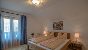 Une chambre à coucher avec un lit en bois, deux tables de chevet avec des lampes, un tableau au mur et une fenêtre avec des rideaux.