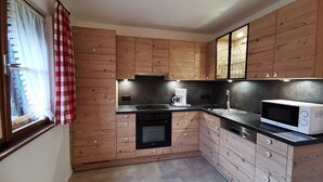 Une cuisine compacte dotée de meubles en bois, d’un four encastré, d’un four à micro-ondes et d’une machine à café.