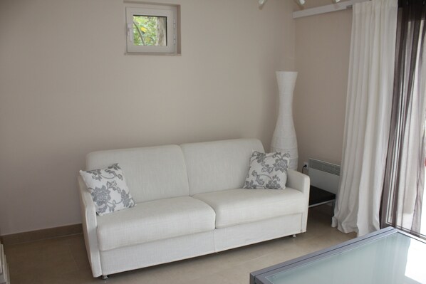 A white sofa with floral cushions, a small picture frame on the wall, and a radiator. - authentic Dalmatian stone house (Splitska)