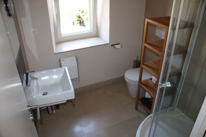 A bathroom with a white sink, a toilet, and a glass shower enclosure. - authentic Dalmatian stone house (Splitska)