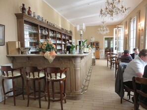 Eine Bar mit Holzsitzen, einer Theke mit Gläsern und einer Kristallleuchtre.