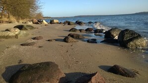 En strand med stora stenar och fri utsikt över havet.