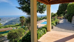 A covered outdoor area with a pool, surrounded by greenery and overlooking a scenic landscape. - Holiday villa with pool, large terrace and great sea and far view. (Gattières)