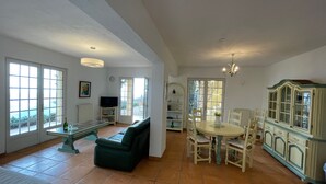 A spacious living area with a sofa, a dining table with chairs, a television, and a cabinet. - Holiday villa with pool, large terrace and great sea and far view. (Gattières)
