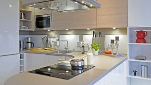Une cuisine moderne dotée d’un îlot central, d’un four à micro-ondes encastré et d’appareils électroménagers en acier inoxydable.