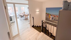 Un escalier mène à une salle à manger d’où l’on peut admirer la plage à travers une grande fenêtre.