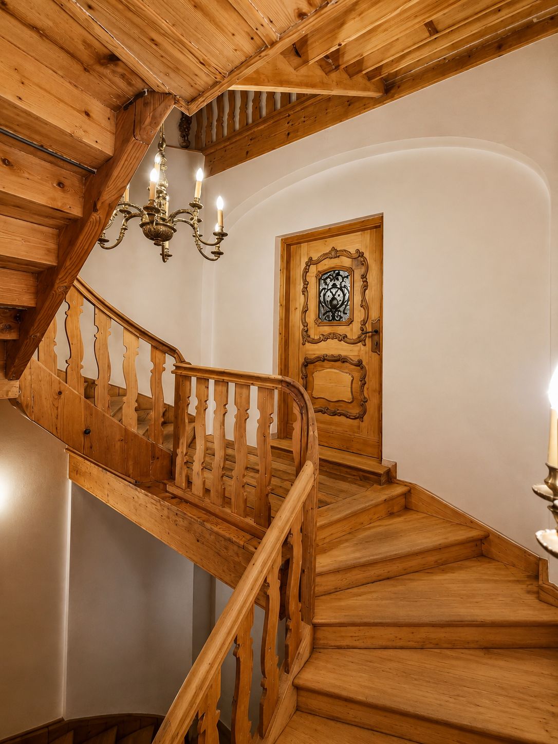 A wooden staircase with a handrail and a door with an ornate design.
