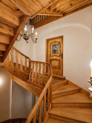 A wooden staircase with a handrail and a door with an ornate design.