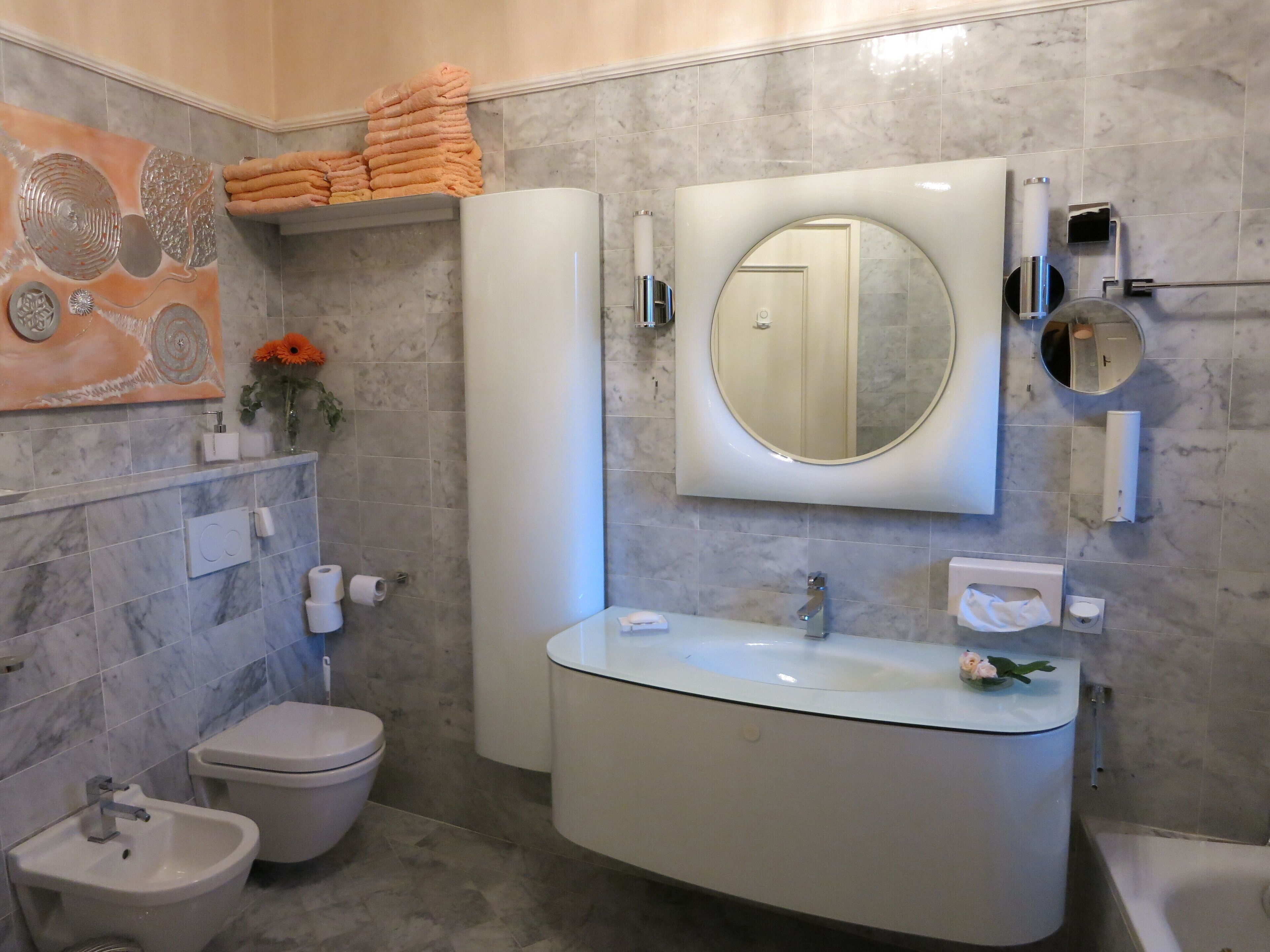 Une salle de bain moderne équipée de toilettes, d’un bidet, d’un lavabo et d’un grand miroir.