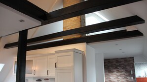 A kitchen with white cabinets, a countertop, and a brick wall in the background. - EXCLUSIVE APARTMENT CENTER NOW (Celle)