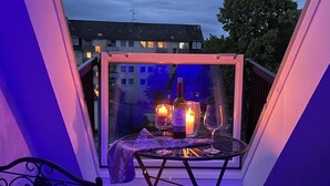 A balcony with a table set for two, featuring a bottle and glasses, and two candles. - EXCLUSIVE APARTMENT CENTER NOW (Celle)