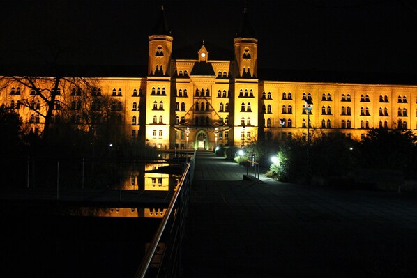 A large, illuminated building with two towers and a central entrance. - EXCLUSIVE APARTMENT CENTER NOW (Celle)