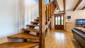 Eine Holztreppe mit einer Steinsäule und einem Fernseher im Hintergrund.