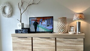 A wooden entertainment unit with a television, a woven lamp, and a decorative branch.