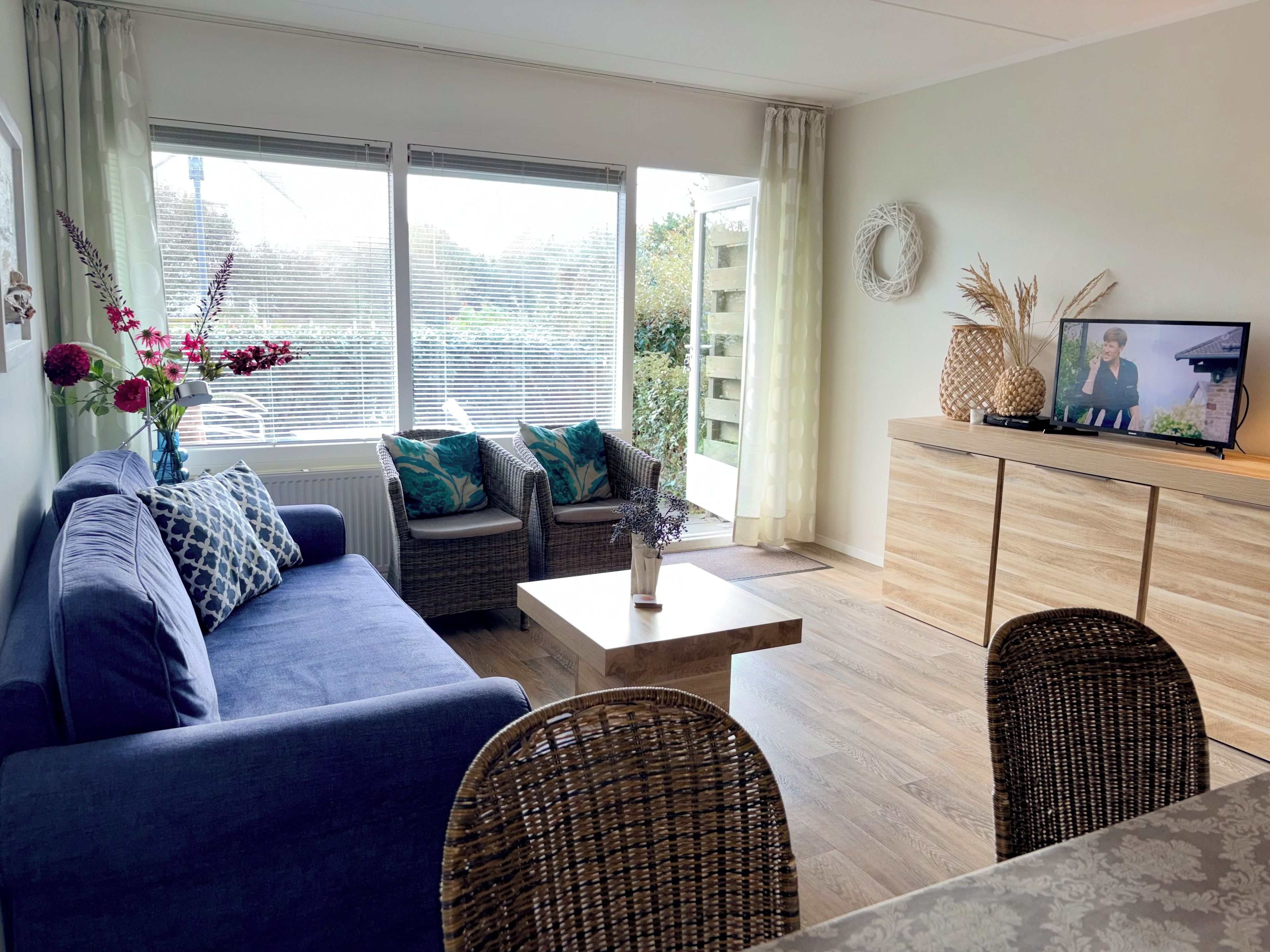 A modern living room with a sofa, two armchairs, a coffee table, and a television on a wooden cabinet.